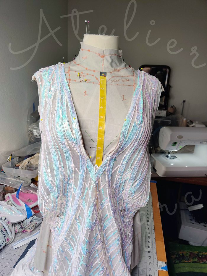 Sequined bodice pinned on a dress form with measurements and fit markings for the neckline